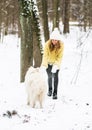 Pretty Young Woman in Snowy Winter Forest Park Walking Playing with her Dog White Samoyed Royalty Free Stock Photo