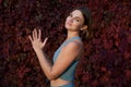 Pretty young woman in sport blue top in the park next to the grape leaves wall