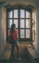 Pretty young woman standing by a window looking at the landscape. Royalty Free Stock Photo