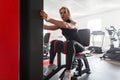 Pretty young woman in stylish black sportswear in sneakers works out on a simulator in a fitness studio. Girl does exercises