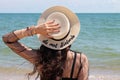 Pretty young woman in summer vacation wearing straw hat enjoying the view at the ocean