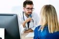 Pretty young woman talking with handsome young doctor about her health in the consultation. Royalty Free Stock Photo