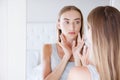 Pretty young woman touching her face while looking at the mirror, beauty concept,skin care,plastic surgery Royalty Free Stock Photo