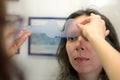 Pretty young woman undergone eye pupil size dimensions test with ophthalmologist optometrist optician Royalty Free Stock Photo