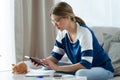 Pretty young woman using calculator and counting her savings while sitting on sofa at home Royalty Free Stock Photo