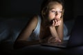Pretty, young woman using her laptop computer in bed Royalty Free Stock Photo