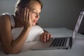 Pretty, young woman using her laptop computer in bed Royalty Free Stock Photo