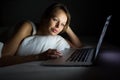 Pretty, young woman using her laptop computer in bed Royalty Free Stock Photo