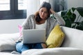 Pretty young woman using her laptop while sitting on sofa at home Royalty Free Stock Photo