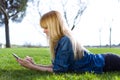 Pretty young woman using her mobile phone while lying on grass in the park. Royalty Free Stock Photo