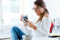 Pretty young woman using her mobile phone in the office. Royalty Free Stock Photo