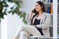 Pretty young woman using her mobile phone in the office. Royalty Free Stock Photo