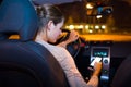 Pretty young woman using her smart phone while driving her car Royalty Free Stock Photo