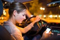 Pretty young woman using her smart phone while driving her car Royalty Free Stock Photo