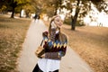 Pretty young woman walking in autumn park and using a mobile phone Royalty Free Stock Photo