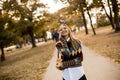 Pretty young woman walking in autumn park and using a mobile phone Royalty Free Stock Photo