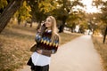 Pretty young woman walking in autumn park and using a mobile phone Royalty Free Stock Photo