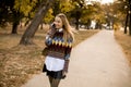 Pretty young woman walking in autumn park and using a mobile phone Royalty Free Stock Photo