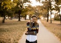 Pretty young woman walking in autumn park and using a mobile phone Royalty Free Stock Photo