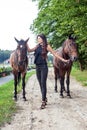 Pretty young woman walking two horses Royalty Free Stock Photo