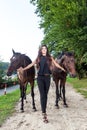 Pretty young woman walking two horses Royalty Free Stock Photo