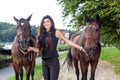 Pretty young woman walking two horses Royalty Free Stock Photo