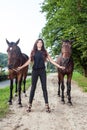 Pretty young woman walking two horses Royalty Free Stock Photo