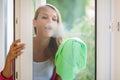 Pretty, young woman washing windows of her household Royalty Free Stock Photo