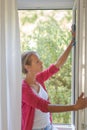 Pretty, young woman washing windows of her household Royalty Free Stock Photo