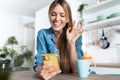 Pretty young woman waving hand while making video call with smartphone during morning tea in the kitchen at home Royalty Free Stock Photo