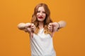 Pretty young woman with wavy redhead, wearing white t-shirt showing thumb down. Dislike, failure gestures concept Royalty Free Stock Photo