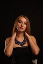 Pretty young woman wearing blue gemstones necklace posing on black background Royalty Free Stock Photo