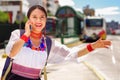 Pretty young woman wearing traditional andean blouse and blue backpack, waiting for bus at outdoors station platform Royalty Free Stock Photo