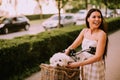 Young woman with white bichon frise dog in the basket of electric bike Royalty Free Stock Photo