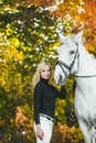 Pretty young woman with a white horse riding in autumn day Royalty Free Stock Photo