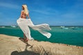 Pretty young woman in white pareo standing on pier near sea Royalty Free Stock Photo