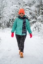 A pretty young woman in a winter wonderland enjoying the snow fashion walk wearing colourful jacket and red cap Royalty Free Stock Photo