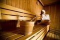 Young woman wrapped in a white towel relaxing in wooden sauna room Royalty Free Stock Photo