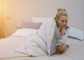 Pretty young woman wrapping in warm blanket and sleeping while sitting on comfortable bed Royalty Free Stock Photo