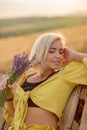 Young woman in yellow among rural field with golden oat field on sunset background Royalty Free Stock Photo