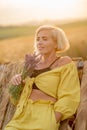 Young woman in yellow among rural field with golden oat field on sunset background Royalty Free Stock Photo