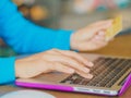 Pretty Young womans hands holding a credit card and using tablet, smartphone and laptop computer