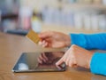 Pretty Young womans hands holding a credit card and using tablet, smartphone and laptop computer