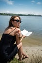 prety young woman in summer day read book near a lake