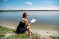 prety young woman in summer day read book near a lake