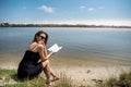 prety young woman in summer day read book near a lake