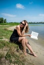 prety young woman in summer day read book near a lake