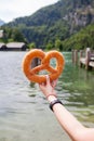 Pretzel in the hands of the girl on the background of the lake in the mountains Royalty Free Stock Photo