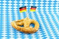 Pretzel with salt and a pair of germany flag on munich background blue rhombus pattern