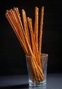 Pretzel sticks in small glass on black background